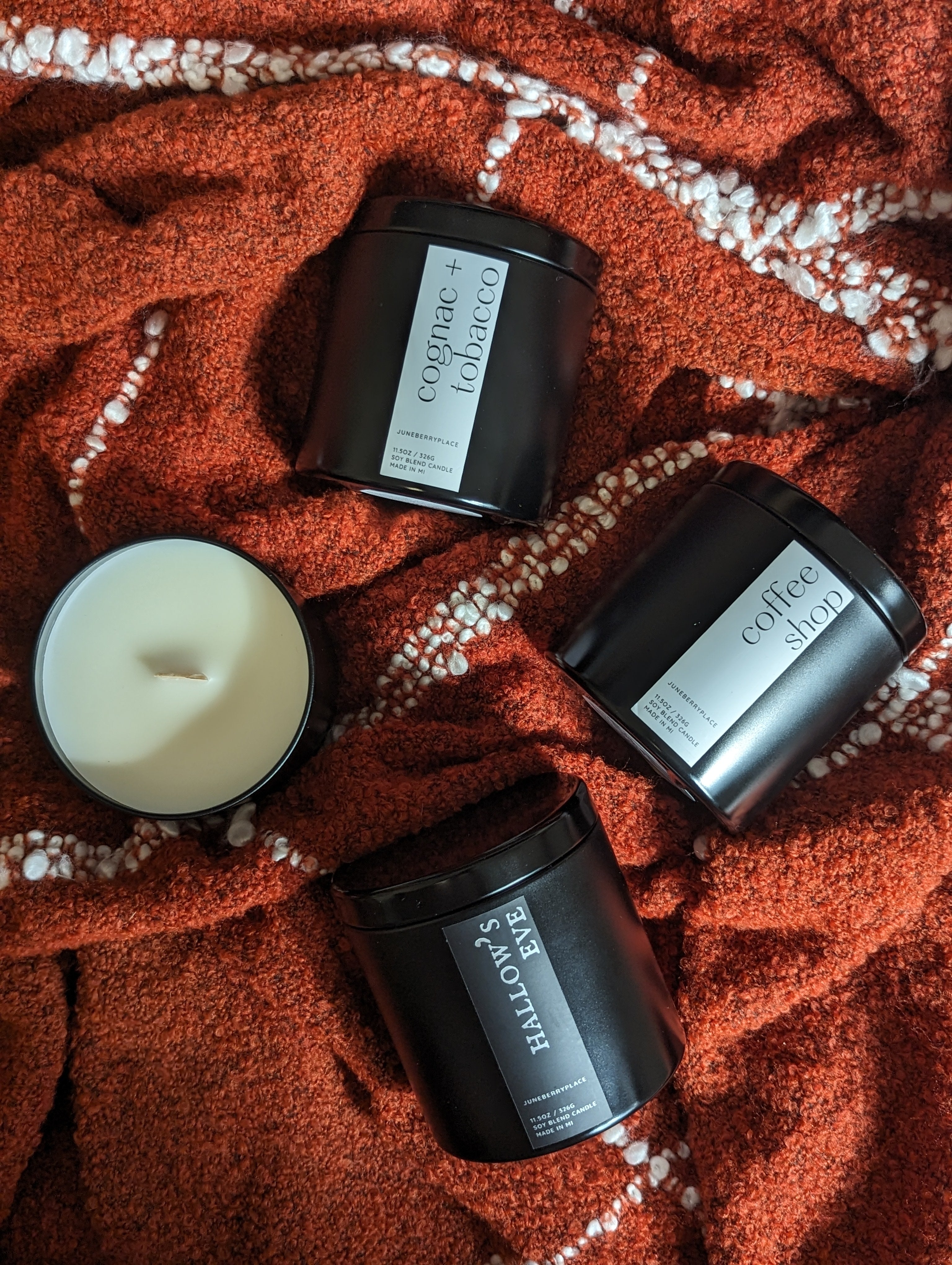 flatlay of Cognac and Tobacoo, Coffee Shop, and Hallow's Eve Fall Candle scents in matte black tins by juneberryplace home fragrances