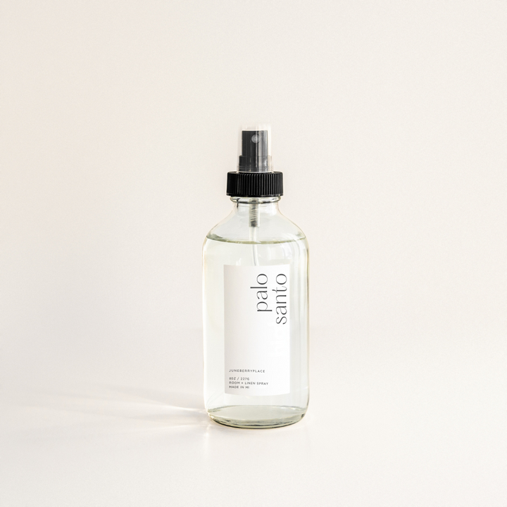 A clear spray bottle labeled 'PALO SANTO' with a black spray nozzle, placed against a neutral background.
